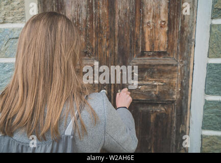 Apertura di una donna molto vecchia porta di legno nella casa. Foto Stock