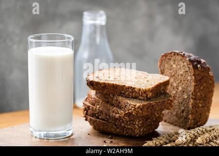 Pane di segale con semi di girasole e bicchiere di latte sulla tavola in legno rustico Foto Stock