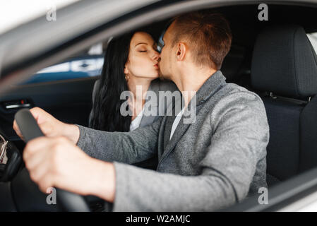 Giovane baciare in auto nuova, showroom. Maschio e femmina i clienti che acquistano il veicolo in concessionaria, automobile vendita, acquisto auto Foto Stock