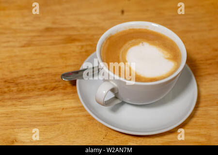 Cappuccino in tazza bianca con piattino su un legno naturale tabella Foto Stock