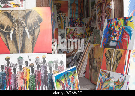 Un giovane artista che lavora su un dipinto a vendere nel suo stallo in Stone Town Zanzibar. Foto Stock