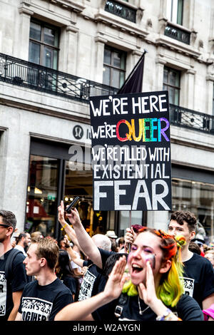 6 Luglio 2019 - segno targhetta dice "Siamo qui, siamo queer, siamo pieni di timore esistenziale', London Pride Parade, REGNO UNITO Foto Stock