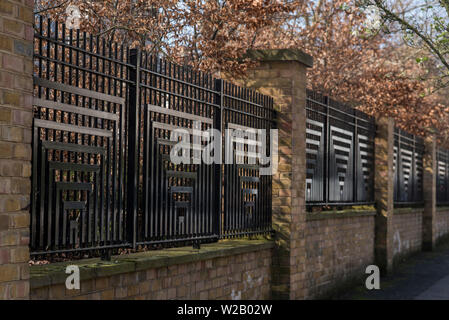 Nero decorativo ringhiere inset tra pilastri in mattoni formano il perimetro e porte intorno a Londra Sud proprietà. Foto Stock
