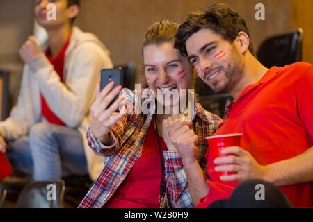 Gruppo di sostenitori dello sport stadium tenendo selfie Foto Stock