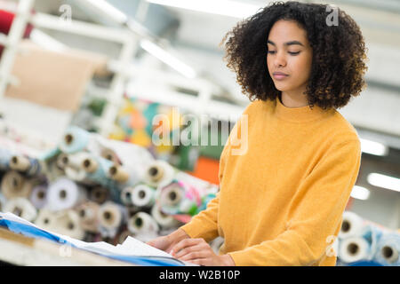 Donna che lavorano in campo industriale occupato sul luogo di lavoro di cucitura Foto Stock