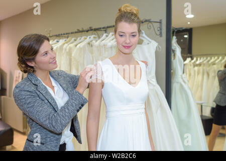 Donna con abito nuziale tutto il montaggio nella boutique Foto Stock