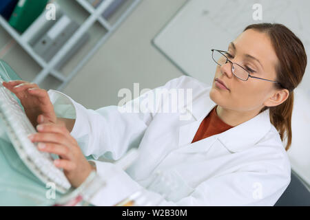 Chirurgo femmina usando un computer portatile contro dati blu Foto Stock
