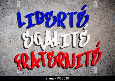Motto nazionale della Francia (traduzione inglese: Libertà, Uguaglianza, Fraternità) scritto in francese blu, bianco e rosso tricolore in testo graffiti Foto Stock