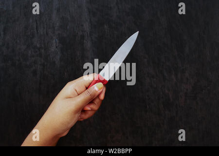 Pelle marrone Ragazza con coltello su legno nero lo sfondo della scheda Foto Stock