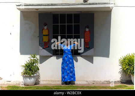 Una giovane bella donna indiana modello in un vestito blu divertendosi e in posa di fronte alla finestra di un cinese cafe con graffiti illustrazione sulla parete. Foto Stock