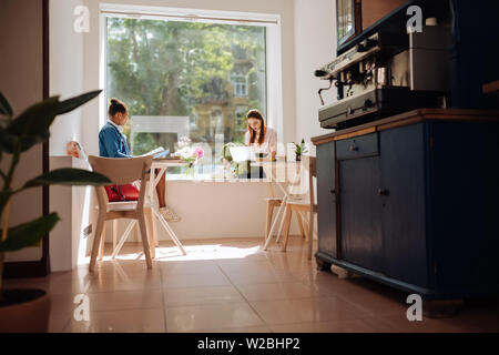 Due freelance. Grave femmina bruna piegando la testata durante la digitazione di rispondere alla posta elettronica Foto Stock