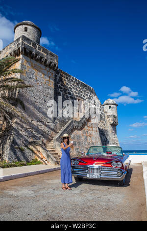 Giovane donna e un 1959 Dodge Custom leale Lancer Convertible, Cojimar Fort, Havana, Cuba (MR) Foto Stock