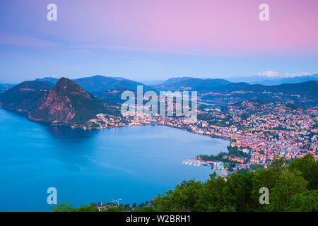 Vista in elevazione sopra Lugano dal Monte Bre illuminata di sunrise, Lugano, Lago di Lugano Ticino, Svizzera Foto Stock