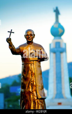 San Salvador El Salvador, Dawn, Salvatore del mondo Plaza, statua dell Arcivescovo Oscar Romero, ufficioso Patrona di El Salvador, assassinato all'inizio del paese la guerra civile nel 1980, sullo sfondo il monumento al Divino Salvatore del mondo, Monumento al Divino Salvador Del Mundo, Statua di Gesù Cristo in piedi su una sfera globale del pianeta Terra, identifica e rappresenta El Salvador e Salvadorians in tutto il mondo Foto Stock