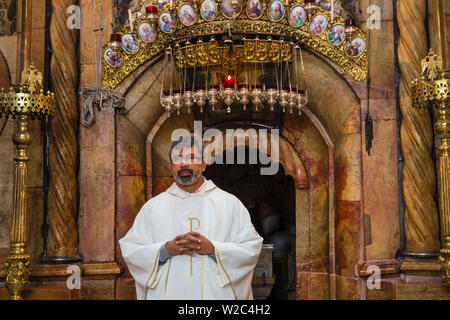 Israele, Gerusalemme, la Chiesa del Santo Sepolcro, sacerdote di fronte alla tomba di Gesù Foto Stock