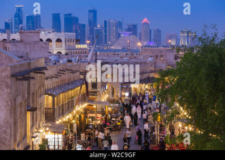 Il Qatar Doha, Souq Waqif, rifatti area bazaar, vista in elevazione con West Bay grattacieli da uno degli storici Souq alberghi, crepuscolo Foto Stock