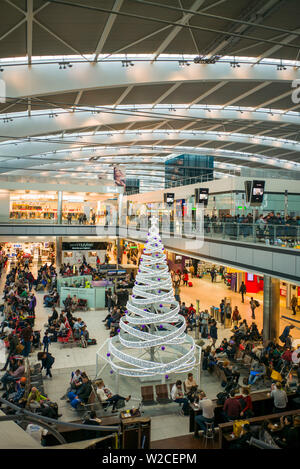 Inghilterra, Londra Heathrow International Airport, terminale 5, vista in elevazione uomo lobby con albero di Natale Foto Stock