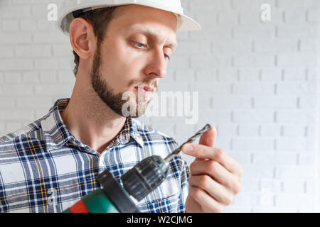 Repairman lavora con il trapano elettrico. Guardando a bit rotto Foto Stock