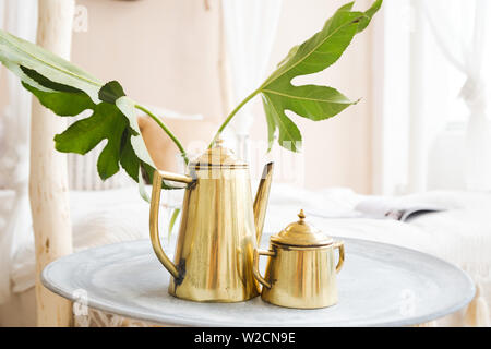 Foto di golden teiera è su un vassoio accanto al letto Foto Stock