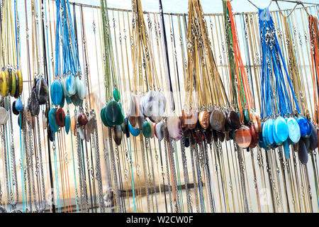 Molti ciondoli gemma fatta di colorate pietre naturali appeso nel negozio di articoli da regalo. Raccolta di diverse collana la vendita sul mercato di strada Foto Stock