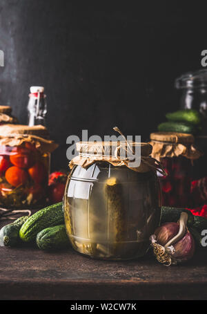 Harvest preservare concetto. Vaso di vetro con fermentato cetriolo sottaceto on dark cucina rustica tavolo con altri Conserva per per la stagione invernale. Cannin Foto Stock