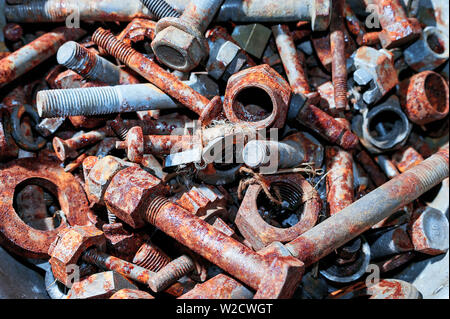 Vista dall'alto in basso di Rusty bulloni, dadi, rondelle in un contenitore di acciaio. Foto Stock