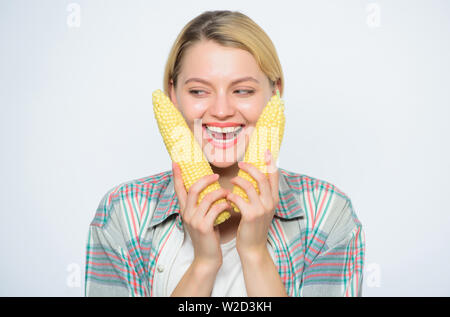 La raccolta del granoturco. Ragazza attesa mais mature. Cibo vegetariano e sano e naturale prodotti organici. Menù vegetariano. Cibo sano concetto. Cibo portare la felicità. Donna tenere giallo pannocchia di sfondo bianco. Foto Stock