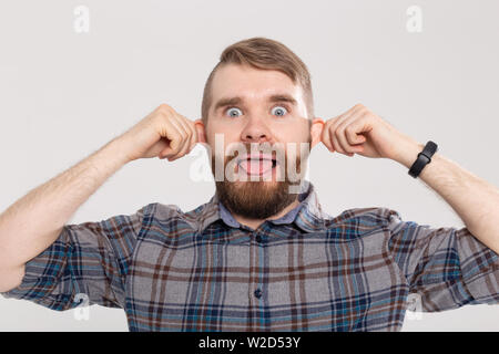 Funny crazy giocoso uomo bello in plaid shirt rendendo silly muso di scimmia il rigonfiamento delle orecchie che mostra la linguetta. Guy avente divertente, eccitante gioco trucchi sciocco umore Foto Stock