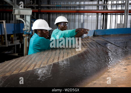 Miniere di titanio sabbie minerali. Impianto di separazione dei materiali. Operatori metallurgici che lavorano su tavoli di vibrazione o scuotimento Wilfley a gravità umida. Foto Stock