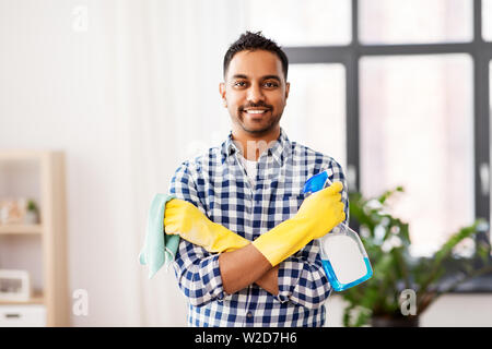 Sorridente uomo indiano con detergente pulizia a casa Foto Stock