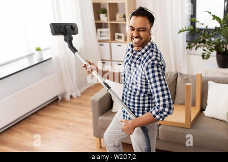 Uomo in cuffie con aspirapolvere a casa Foto Stock