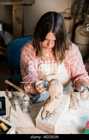 Signora scultore lavorando nel suo studio, ceramis artista con le mani in mano la realizzazione di oggetti di argilla naturale Foto Stock