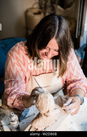 Signora scultore lavorando nel suo studio, ceramis artista con le mani in mano la realizzazione di oggetti di argilla naturale Foto Stock