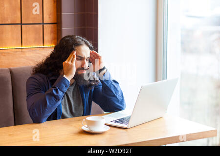 Ritratto di pensosa bel giovane uomo adulto libero professionista in uno stile informale in seduta cafe con laptop, cercando di concentrare e ricordare alcune informa Foto Stock