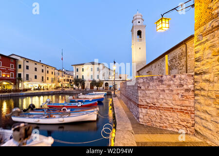 Le barche attraccate al porto antico di Lazise e la chiesa di San Nicolò. Il lago di Garda, provincia di Verona, Veneto, Italia, Europa. Foto Stock