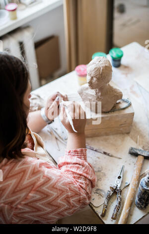 Signora scultore lavorando nel suo studio, ceramis artista con le mani in mano la realizzazione di oggetti di argilla naturale Foto Stock