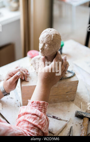 Signora scultore lavorando nel suo studio, ceramis artista con le mani in mano la realizzazione di oggetti di argilla naturale Foto Stock