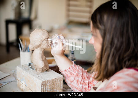 Signora scultore lavorando nel suo studio, ceramis artista con le mani in mano la realizzazione di oggetti di argilla naturale Foto Stock