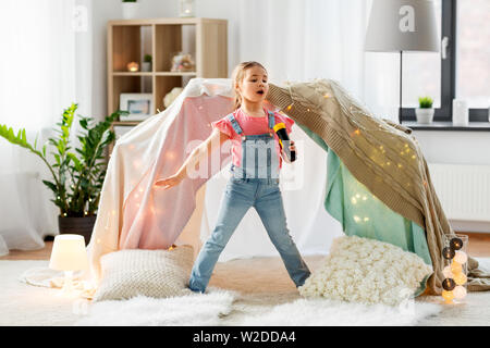 Bambina con microfono giocattolo cantare a casa Foto Stock