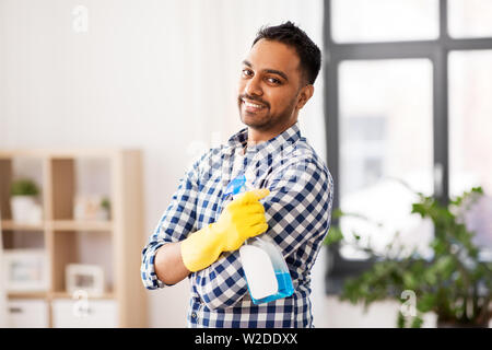 Sorridente uomo indiano con detergente pulizia a casa Foto Stock