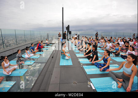 Bangkok, Tailandia. 7 Luglio, 2019. Gli appassionati di Yoga frequentare il vino sunrise yoga classe presso la terrazza sul tetto di Mahanakhon skywalk a Bangkok, Thailandia, Luglio 7, 2019. Vino di sunrise yoga unisce la gioia di bere il vino con lo yoga tradizionale pone mentre il bilanciamento delle bevande, sorseggiando e tostatura. Credito: Rachen Sageamsak/Xinhua/Alamy Live News Foto Stock