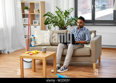 Uomo con notebook computer dopo la pulizia della casa Foto Stock