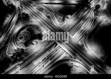Vista aerea al di sopra della trafficata autostrada incroci stradali di notte. L'autostrada intersezione cavalcavia stradali. In bianco e nero Foto Stock