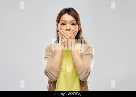 Spaventata donna asiatica su sfondo grigio Foto Stock