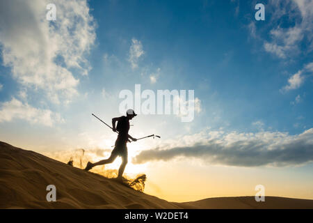 62 enne trail runner il training su vaste dune di sabbia a Maspalomas a Gran Canaria a sunrise. Foto Stock