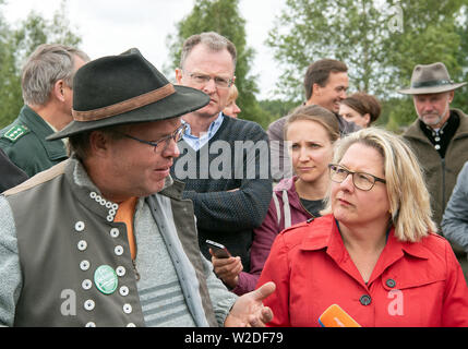 Kirchhain Doberlug, Germania. 08 Luglio, 2019. Svenja Schulze (r, SPD), il Ministro per l'ambiente, la conservazione della natura e sicurezza nucleare e pastore Rene Jeronimus (l) converse vicino a pascoli dell'Weißhaus patrimonio naturale sito. Le grandi foreste contigue della Nazionale del Patrimonio naturale su ex proprietà militare offrono lupi ideale e habitat indisturbato. Credito: Soeren Stache/dpa/Alamy Live News Foto Stock