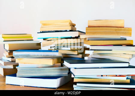 Diverse pile di diversi libri su un tavolo di legno , libri usati e nuovi , Foto Stock