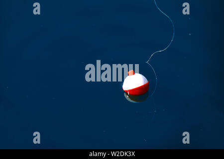 Rosso e bianco pesca flottante bobber con pesce bianco sulla linea blu scuro acqua Foto Stock