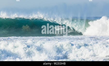 Oceano onda cava grande crash acqua blu con unidentified surfer surf di metropolitana incontrano facce nature power. Foto Stock