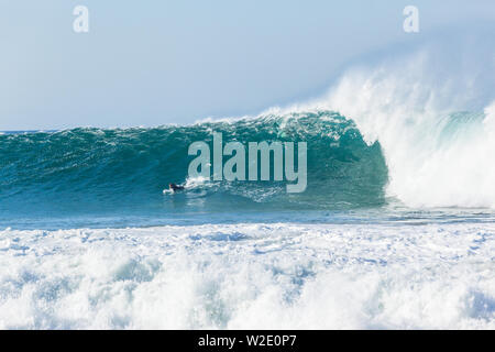 Oceano onda cava grande crash acqua blu con unidentified surfer surf pagaie per la cattura di gonfiarsi incontrano facce nature power. Foto Stock